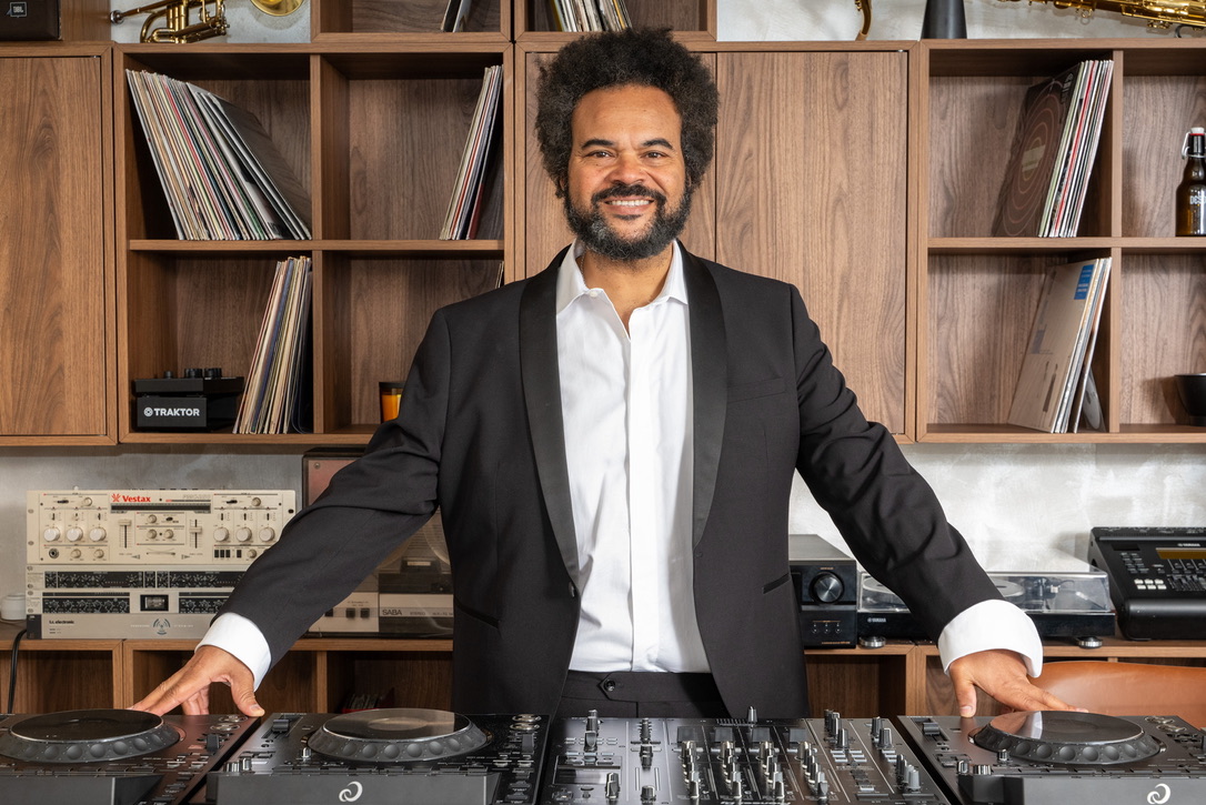 Carlos Jean in the booth, surrounded by vinyl and analogue gear